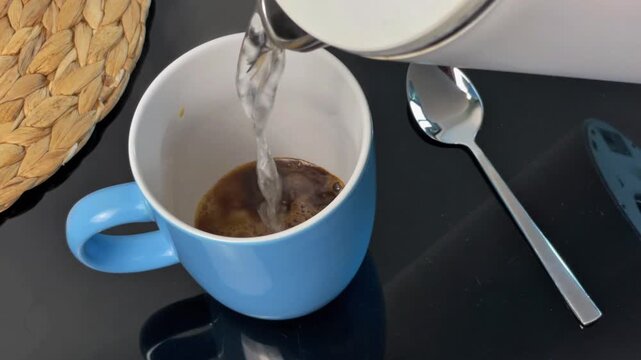 Pour hot boiling water into a cup with instant coffee and condensed milk. This is a homemade way to make a sweet coffee drink.