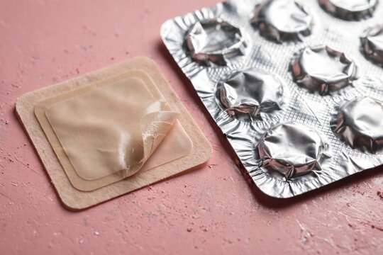 Close-up of a single condom wrapper next to a blister pack of condoms.