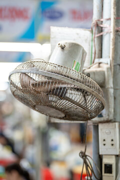 Dirty electric fan clogged and filled with dust sticking on grille at street market in Asia, unwashed greasy metallic fan hanging at vendor stall, unhygienic and unsanitary device source of germs.