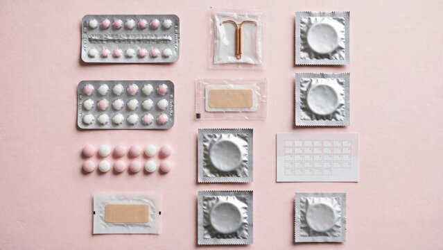 Various Contraceptive Methods Arranged on a Pink Background.