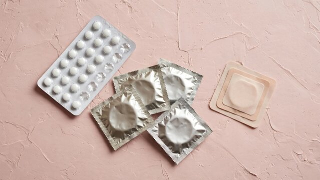Collection of Condoms and Birth Control Pills on a Textured Surface.