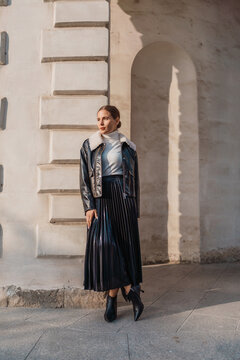 Woman jacket skirt stands near white stone wall outdoors under sunlight for autumn fashion street style concept