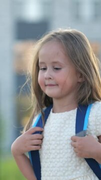 Adorable little girl with a backpack smiling as she proudly walks to her first day of elementary school, feeling a mix of excitement and shyness while looking around at her new surroundings