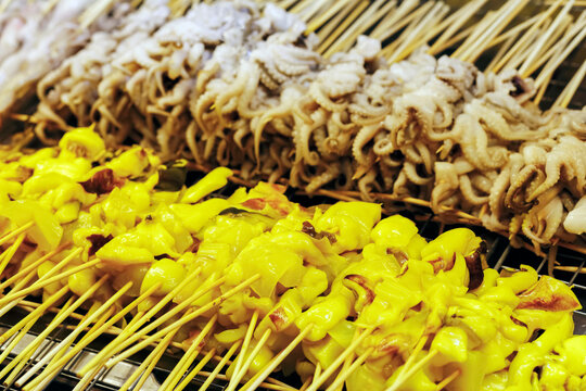 Fresh squid skewers displayed at a seafood market stall, ready for grilling or cooking. Traditional street food ingredients, raw seafood