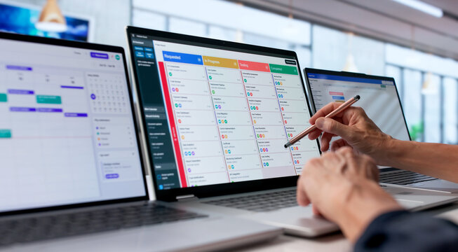 Older Woman Updates Project Tasks On Laptop While Pointing