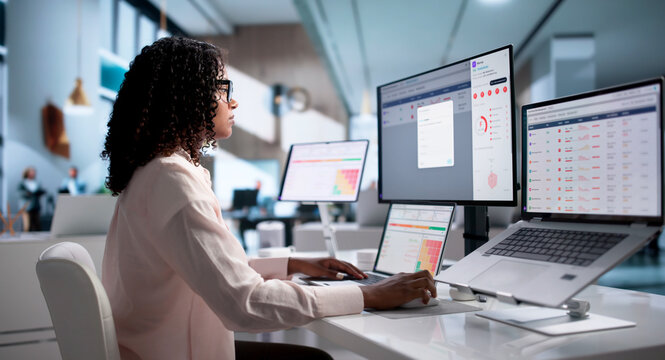 Young African Woman Using Laptop And Desktop
