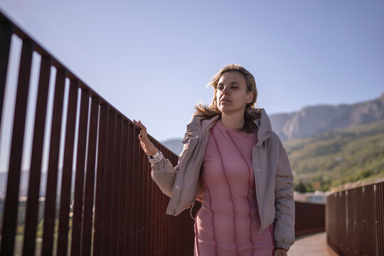 Woman outdoor bridge contemplating view on a modern walkway in the mountains under blue sky