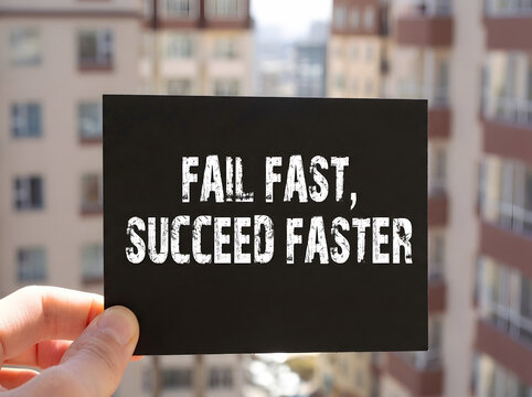 Fail Fast Succeed Faster Inspirational Quote On Black Card Held By Hand With Blurred City Background For Entrepreneurial Mindset And Personal Growth Concept