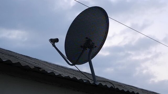 A satellite dish on the roof with the sky in the background