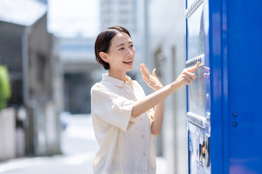 自動販売機で飲み物を買う女性