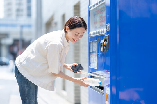自動販売機で飲み物を買う女性