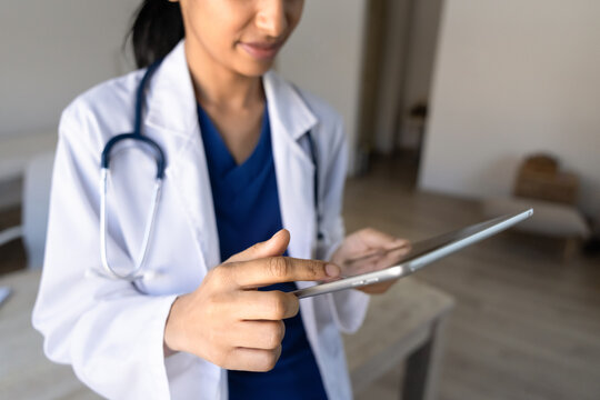 Closeup female doctor working on digital tablet in clinic office, reviewing electronic health records, checking patient data, updating medical report. Healthcare technology use in medicine concept