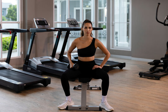 Calm young woman practicing meditation and gentle fitness exercises in a modern gym, combining mindfulness, rest and light workout for a balanced healthy lifestyle.