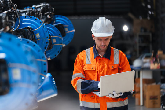 Robotics engineer using laptop for software programming supporting robotic system integration, plant engineering, diagnostics, installation