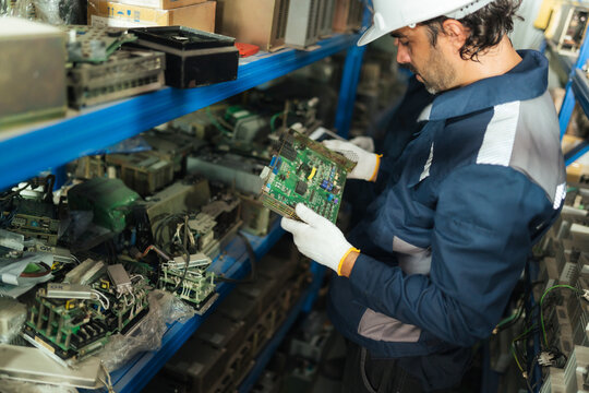 Maintenance technician checks electronic spare part on warehouse shelves, supporting machine customer customization. checking circuit boards, repair planning, inventory control.
