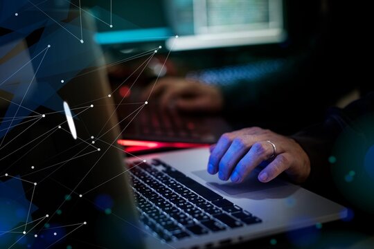 Hands typing on a laptop with digital network graphics overlay.