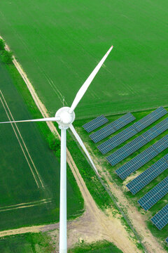 Solar energy panels and wind turbines in rural green landscape