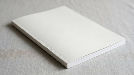 Fototapeta premium Blank white book cover laying on a light wooden table surface. magazine mockup psd
