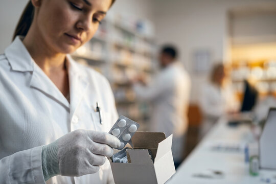 Pharmacist holding medication blister pack in pharmacy