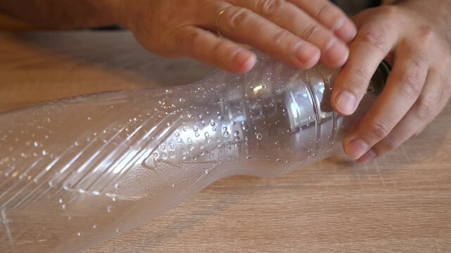 Person intensely rubbing fingers across the surface of an empty plastic bottle in close up. Continuous action with original sound.