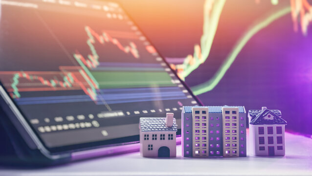market trends and mortgage interest rates analysis. Toy houses against a background of stock market candlestick graphs