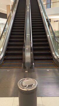 A set of two functioning parallel escalators in an indoor shopping mall providing premium transportation between floors for shoppers and visitors in a vibrant commercial environment