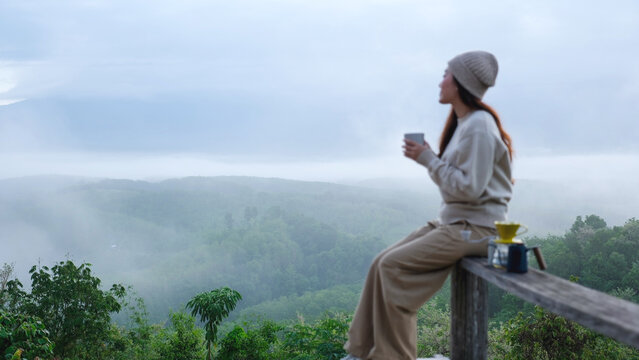 Blurred of a woman drinking coffee while looking at a beautiful foggy mountain and nature view