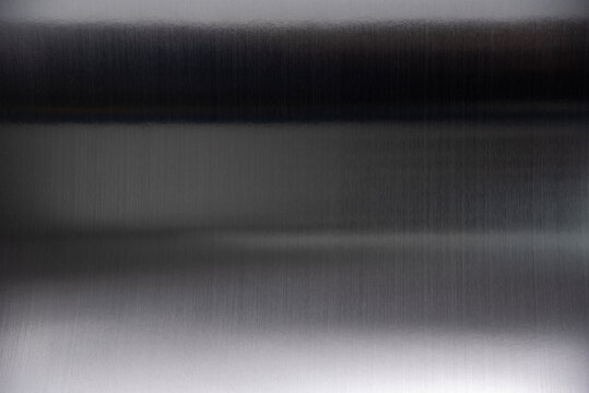 Curved black stainless steel sheet with metallic glare isolated on white background.
