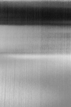 Curved black stainless steel sheet with metallic glare isolated on white background.