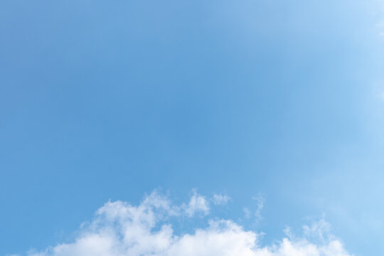 Blue sky with white clouds illuminated by natural light. Clean high resolution background with generous copy space for graphic design.
