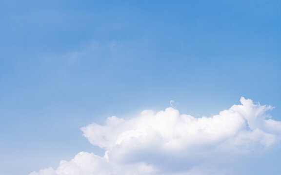 Blue sky with fluffy white clouds and ample copy space. High resolution natural background ideal for graphic design and advertising.