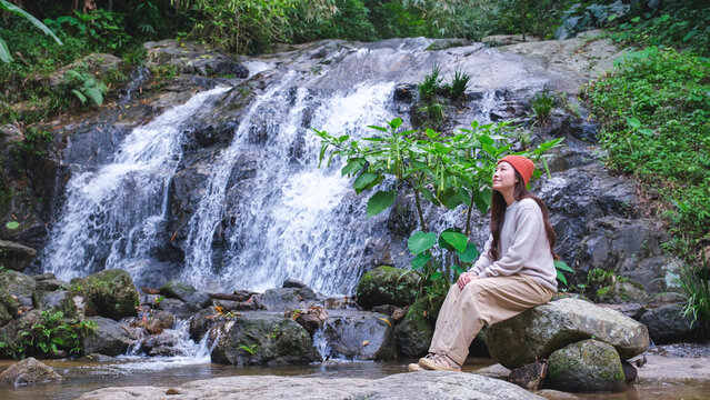 A woman sitting and relaxing by the waterfall in the forest