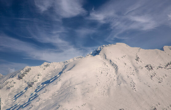 The freezing wind blowing hard between the rocks and snow