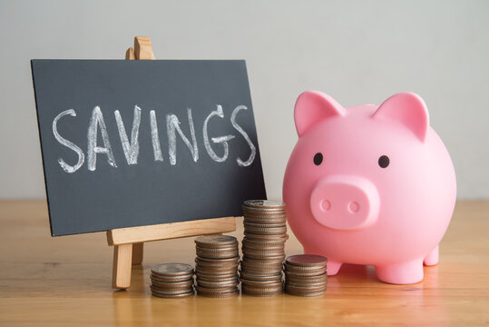 Pink piggy banks, stack coins and SAVINGS hand writing in blackboard on table. Financial planning management, money literacy, savings, personal wealth, money saving, banking finance and so on concept.