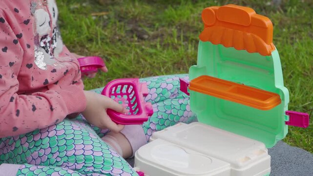 Cute child assembling portable doctor playset in the park, Close up of toddler hands opening  toy doctor suitcase.