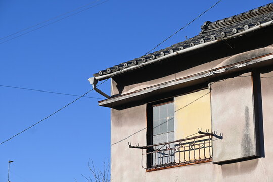 青空を背景にした古い民家の屋根と窓