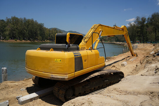 Building process city levee. Excavator dredging pond bank