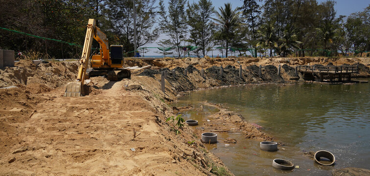 Building process city levee. Excavator dredging pond bank