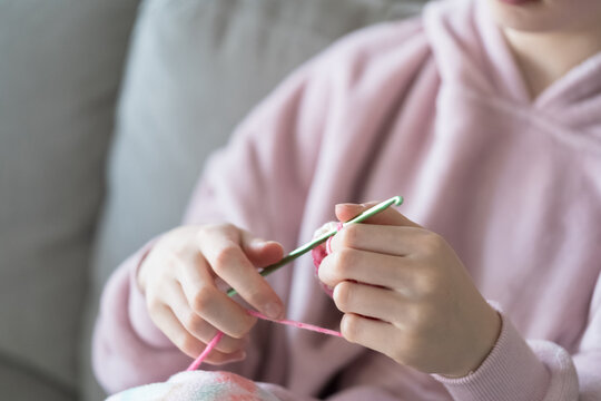 Hands crocheting with pink yarn indoors