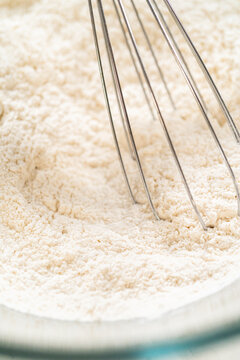 Whisk mixing flour inside glass bowl preparation