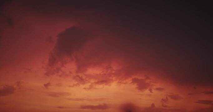Ominous dark rain clouds over fiery red sunset sky timelapse.