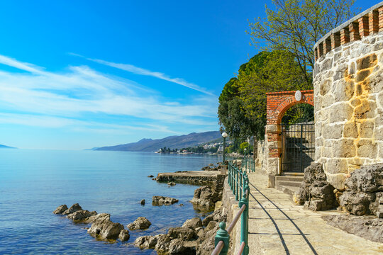 Scenic stone coastal promenade with historic walls overlooking the calm Adriatic Sea in Opatija, Croatia. The famous seaside walkway offers panoramic coastal views under a clear blue sky