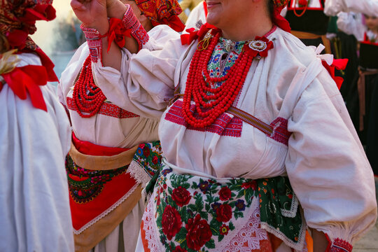 Close-up of women in authentic Croatian folk costumes with embroidered dresses, floral aprons, and traditional red coral necklaces during Ethno Festival in Selce, Croatia 