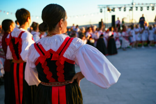 Rear view of performers dressed in authentic Croatian folk costumes preparing for a traditional dance performance during the Ethno Festival, Selce, Croatia 