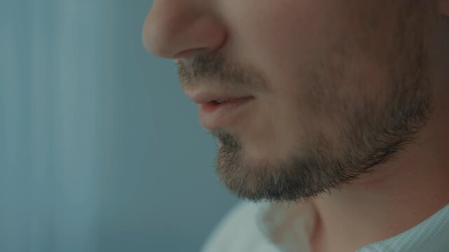 Close-up of the mouth drinking from a cup of coffee or tea. A man's mouth in close-up takes a sip and a slight smile.
