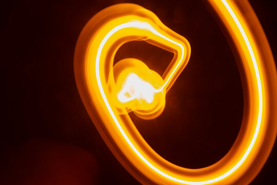 Abstract long exposure of tangled yellow glowing light trails over dark background.