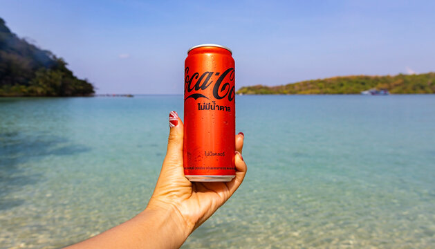 Phuket-Thailand-March-27-2023 :Man hand with Coke Cola softdrink can and a glass a carbonated soft drink produced and manufactured by Coke in thailand