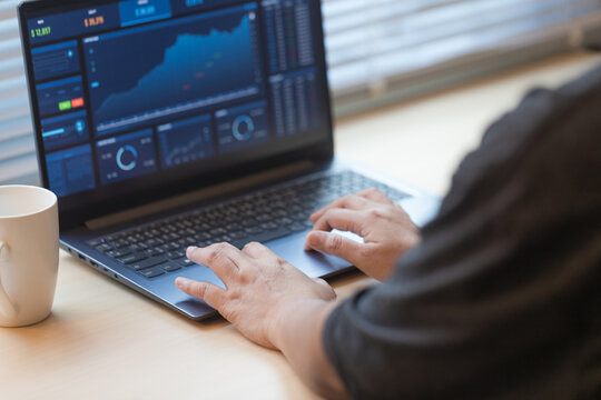 Hands working on a laptop displaying financial data