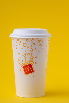 McDonalds paper drink cup with lid on yellow background, fast food drink. White beverage cup Coca-Cola, juice or cocktail. Kyiv, Ukraine - May 24, 2026