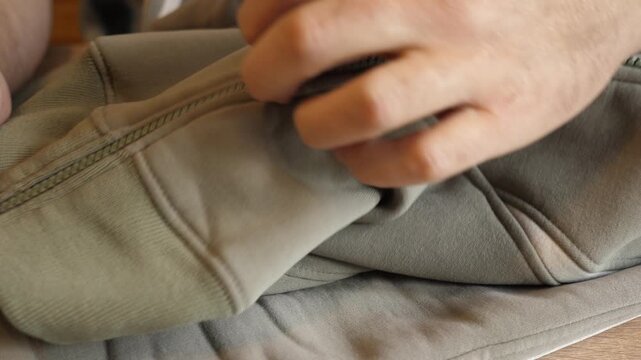 Person inserting the zipper slider into a sweater zipper and smoothly zipping it up in close up. Continuous action with original sound.